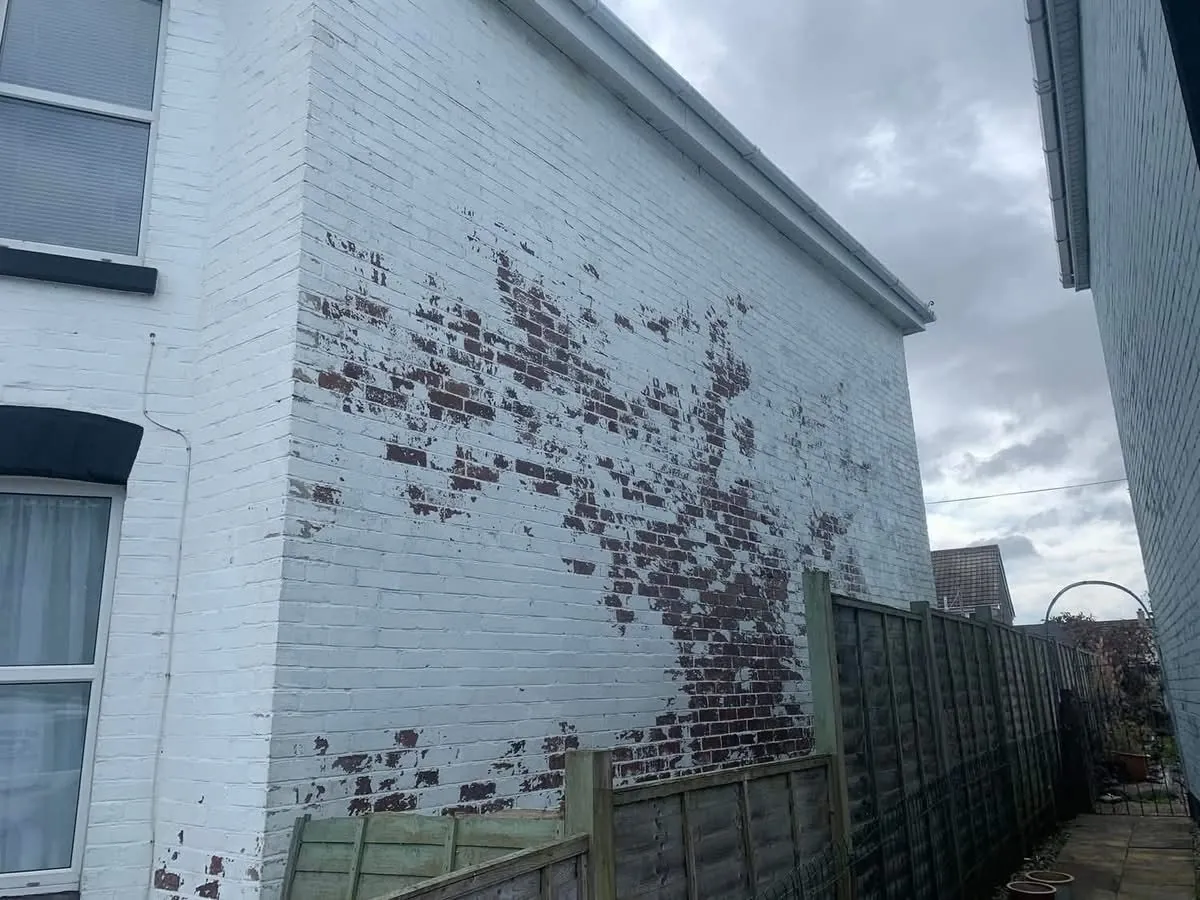 Peeling paint on a brick wall before redecoration in St Blazey